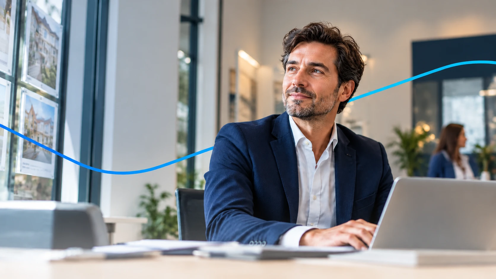 Agent immobilier souriant à son bureau, devant l'écran de son ordinateur
